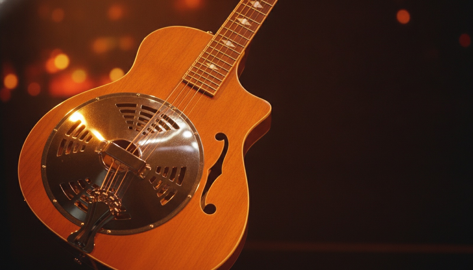 Close-up of a resonator dobro guitar catching stage light