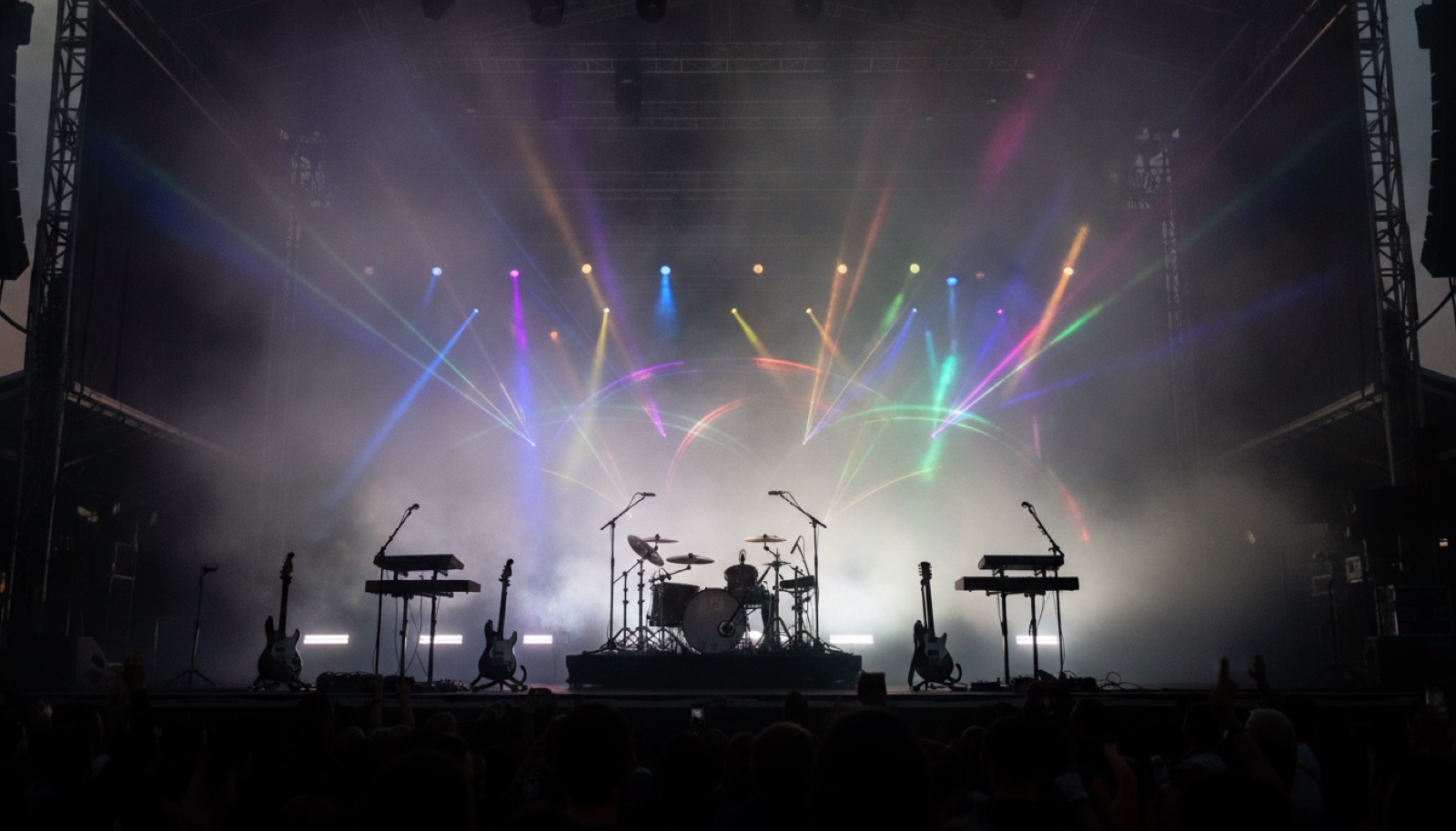 Four musicians on a dark stage silhouetted against colorful stage lighting
